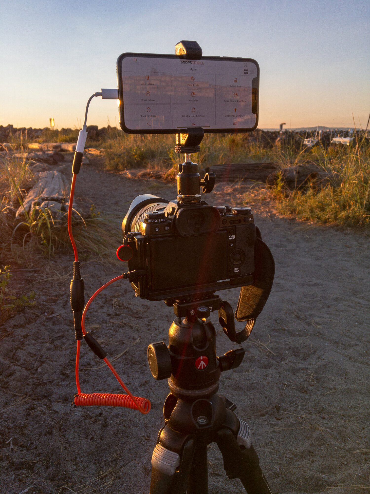 iPhone mounted on a hot-shoe ballhead, with the MIOPS Mobile Dongle connected to the camera.