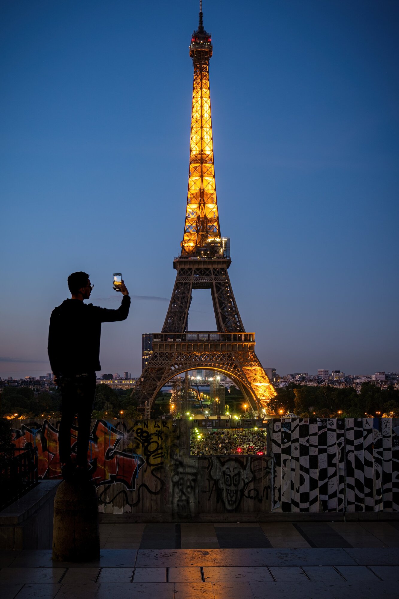 A late-night reveler gets higher up to take a phone snapshot of the Eiffel Tower. (Photo: Jeff Carlson)